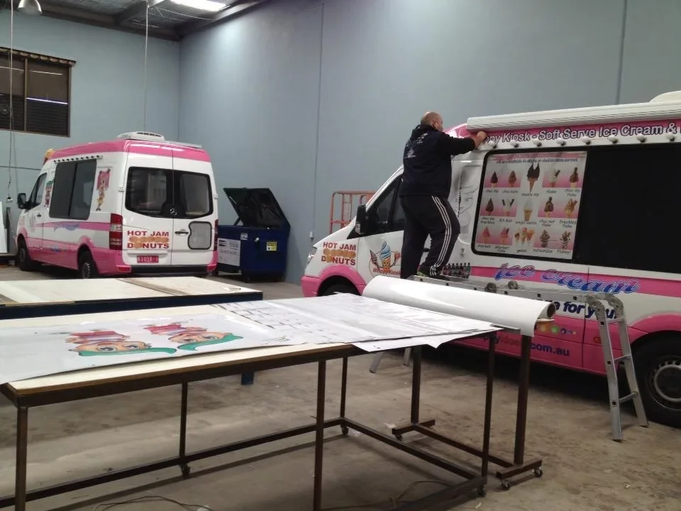 Mr Softy team member applying exterior graphics to an ice cream van inside the van-building workshop