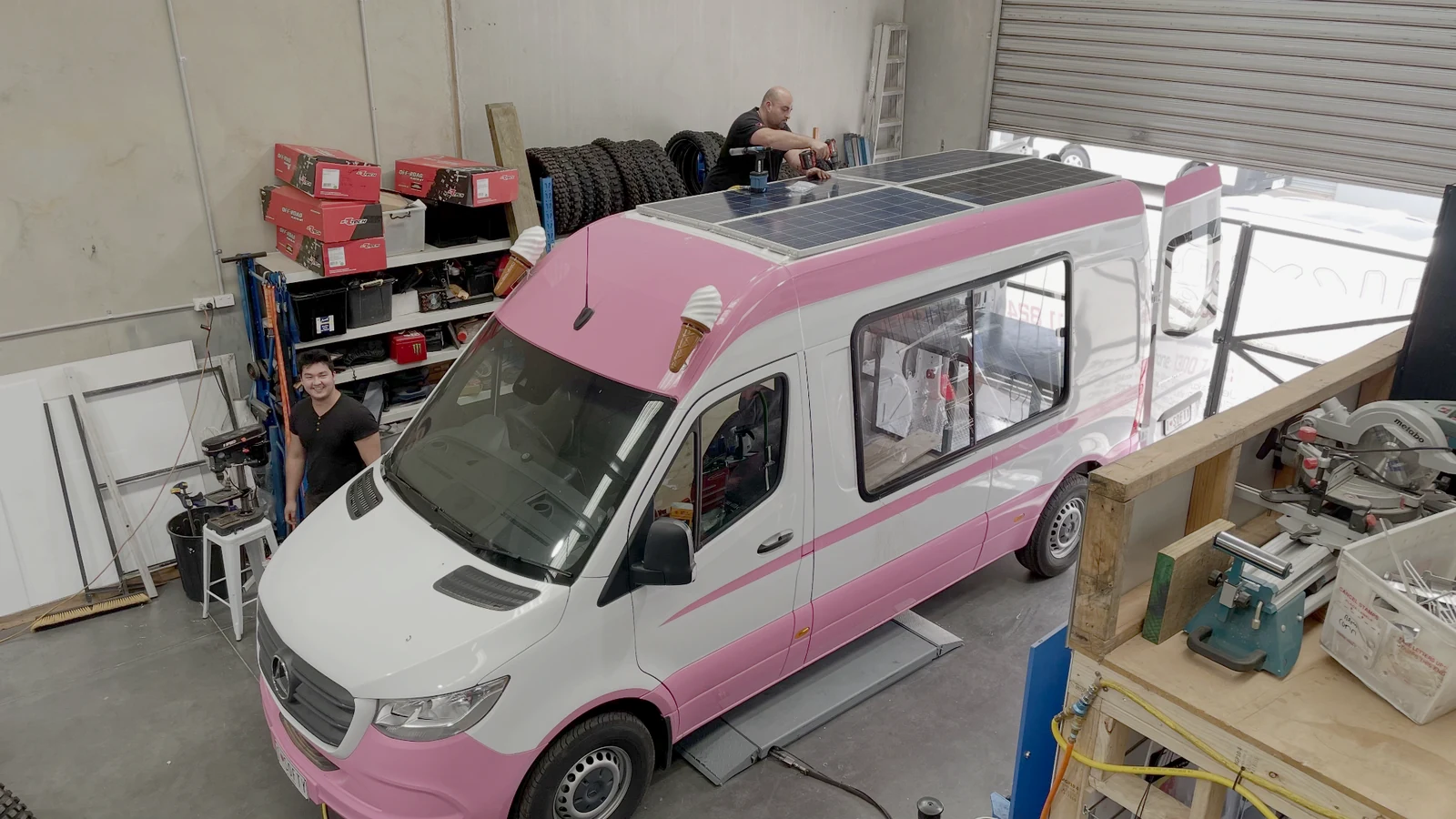 Technicians fitting solar panels to the roof of a new pink and white Mr Softy Mercedes-Benz ice cream van inside the factory