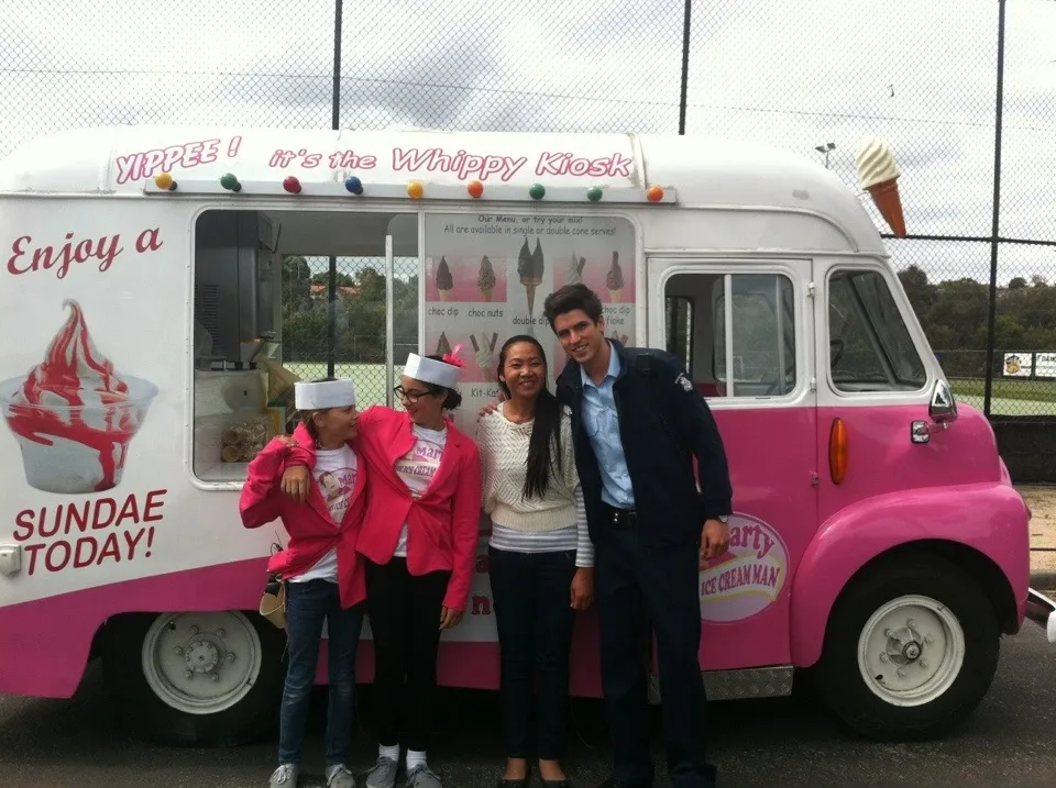 Television presenters and participants standing beside the pink and white ice cream van during Prank Patrol filming